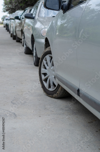 Rows of cars parked on the side of the road in a residential area. Lots of gray cars parallel to the sidewalk. Parallel parking.
