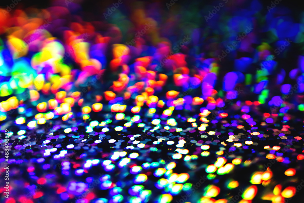 Blurred Neon rainbow glittering lights with glow effect abstract background. Defocused festive twinkle lights bokeh. Modern purple, blue, pink, green dark 80s, 90s design