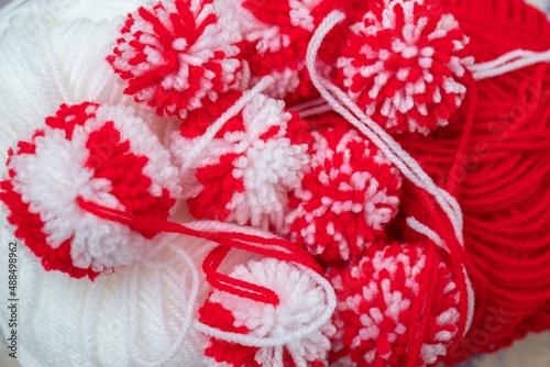 Close up red and white yarn strains of pompoms balls as martenitsa - bulgarian folklore tradition in March Baba Marta day. Shallow depth of focus. Colorful yarn texture background. photo