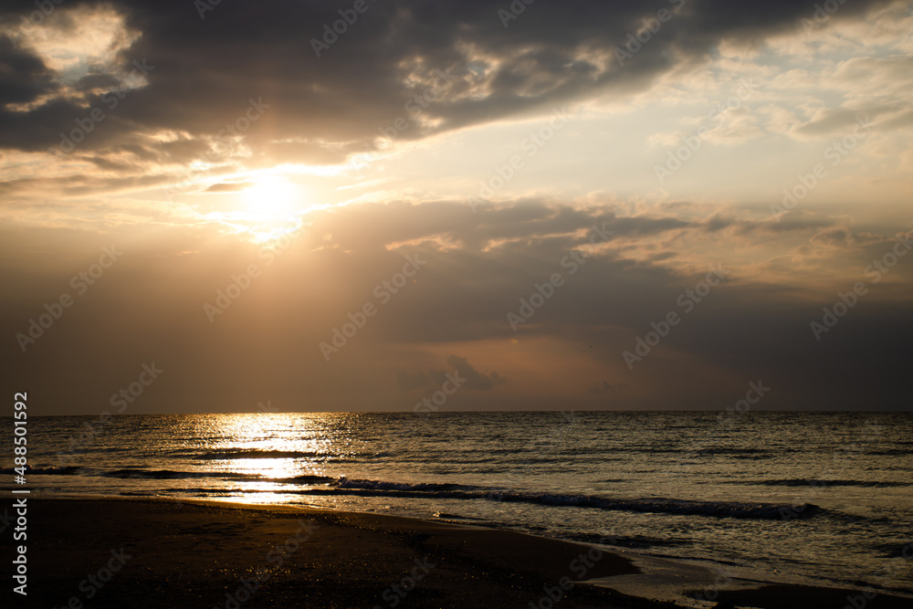 Beautiful sunrise on the sea, the sun's rays pass through the clouds. Calm weather, vacation concept