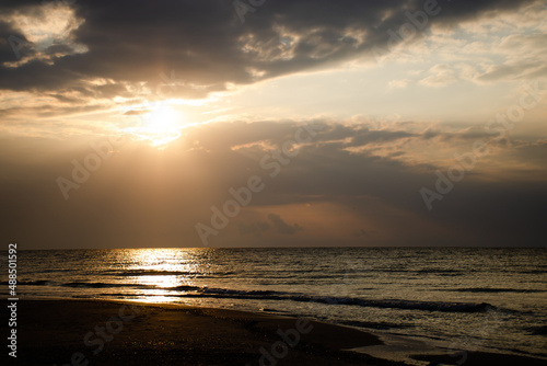 Beautiful sunrise on the sea  the sun s rays pass through the clouds. Calm weather  vacation concept