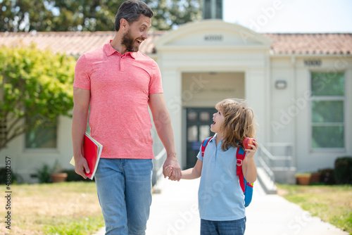 Father and son go to school, education and learning. Parent and pupil of primary school schoolboy with backpack. photo