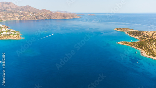 Top view aerial photo from flying drone of a little green, tropical island in open sea. Small beach in ocean with turquoise water with copy space for your advertising