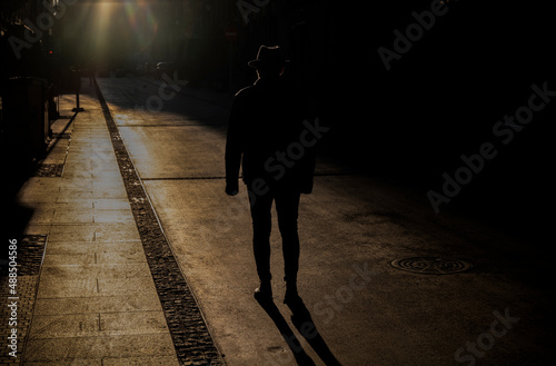 Silhouette of adult man in hat on street during sunset. Madrid, Spain