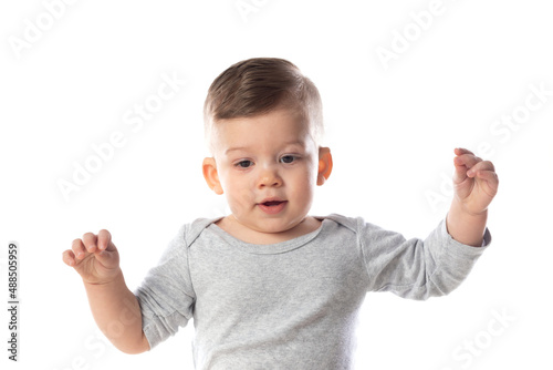 Little smiling baby in bodysuit sitting barefoot on the floor