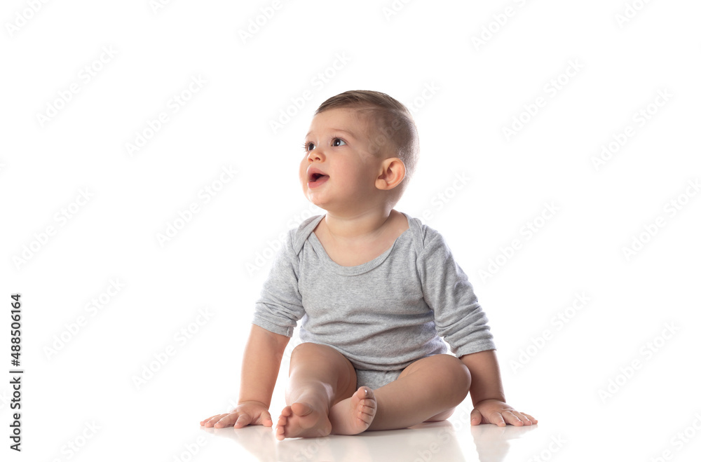 Little smiling baby in bodysuit sitting barefoot on the floor Little smiling baby in bodysuit sitting barefoot on the floor