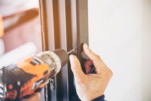 Man doing aluminum frame with glasses and wire screen door and window installation work in construction site
