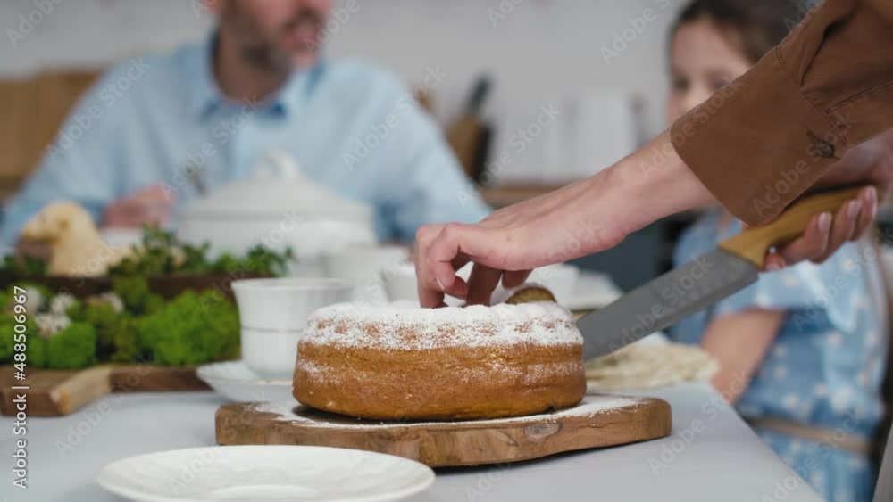 Unrecognizable woman cutting easter cake and passes a piece to the family in the background. Shot with RED helium camera in 8K. Unrecognizable woman cutting easter cake and passes a piece to the family in the background. Shot with RED helium camera in 8K.