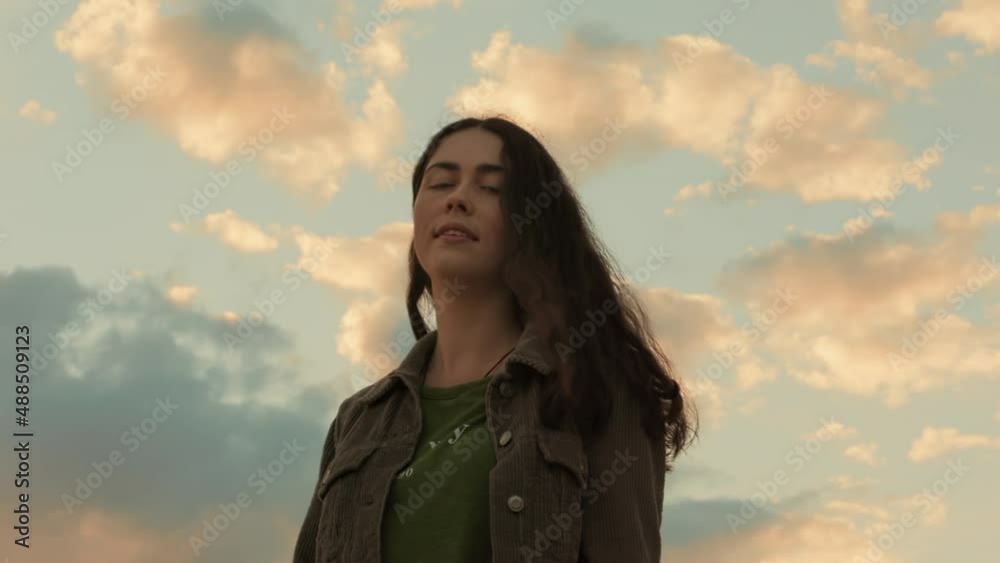 Portrait of a young beautiful smiling woman against a cloudy sunset sky. Side view. The concept of psychology and mental health. Portrait of a young beautiful smiling woman against a cloudy sunset sky. Side view. The concept of psychology and mental health.
