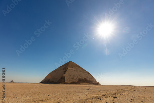 Beauty of one pyramid with sun on the blue sky.
