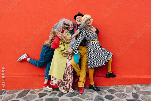Group of eccentric senior citizens having fun against a red background