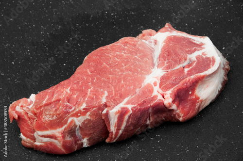 fresh piece of pork meat on a black background. juicy meat for steak on a dark texture. meat processing industry concept. a piece of raw fillet on the countertop. cooking illustration