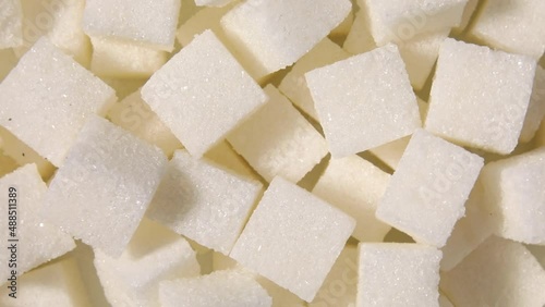 Rotation macro white sugar cubes close up texture background, diet health risks related to diabetes and calorie intake