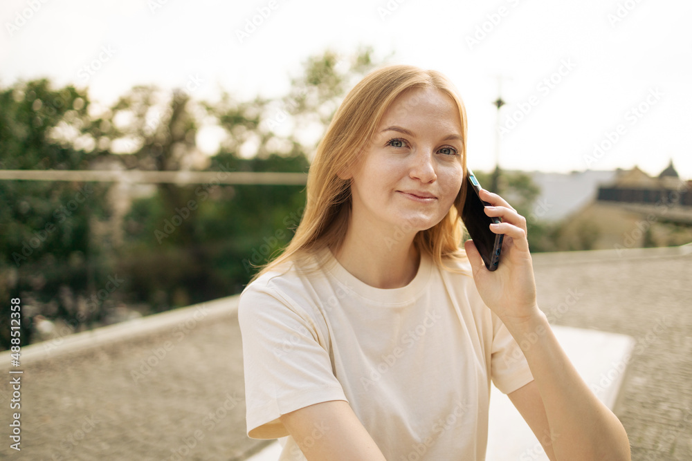 Photo portrait of pretty attractive beautiful blonde hair woman smiling talking on phone outdoors Photo portrait of pretty attractive beautiful blonde hair woman smiling talking on phone outdoors