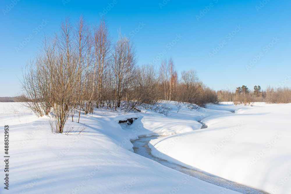 Frozen small river. Winter landscape against the blue sky