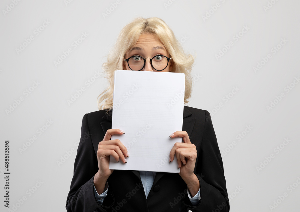 Naklejka premium Shocked female entrepreneur peeking from behind documents, posing over light grey studio background