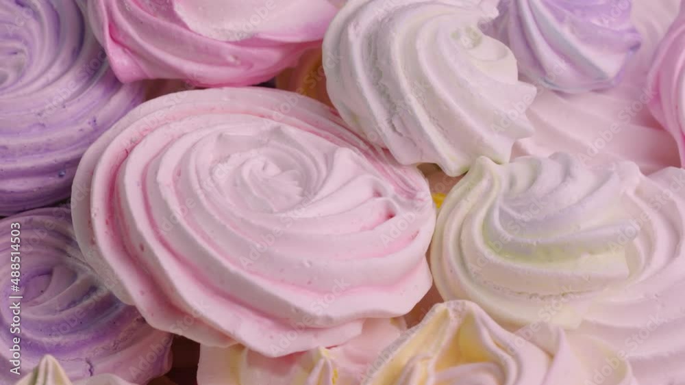 Twirls of sweet meringue rotating close up. French sweets, of protein and sugar cookies pink and purple color. Festive background of sweets for children's birthday. Slow motion ready, 4K at 59.94fps. Twirls of sweet meringue rotating close up. French sweets, of protein and sugar cookies pink and purple color. Festive background of sweets for children's birthday. Slow motion ready, 4K at 59.94fps.