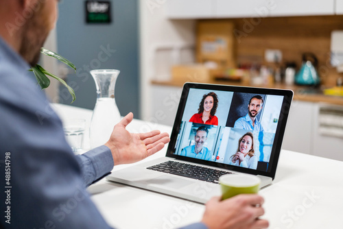 Businessman discussing with colleagues in web conference at home office photo