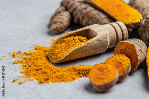 Fototapeta Naklejka Na Ścianę i Meble -  Close-up Turmeric curcumin powder in wooden spoon and fresh curcuma or curcumin on concrete background. Spice, natural coloring, alternative medicine. Long banner format. top view