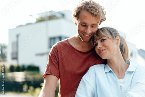 Smiling affectionate couple in front of house photo