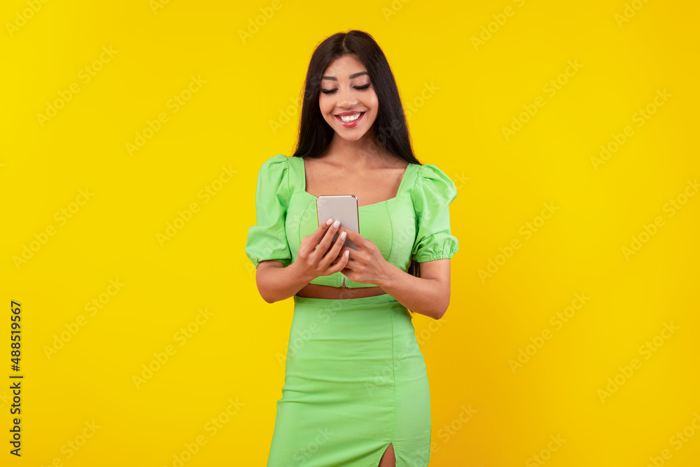 Happy young woman using mobile phone at studio Happy young woman using mobile phone at studio