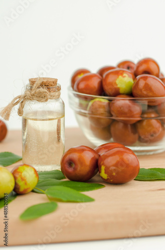 Foto Jojoba oil in bottle with cork and fresh jojoba fruit on wooden table