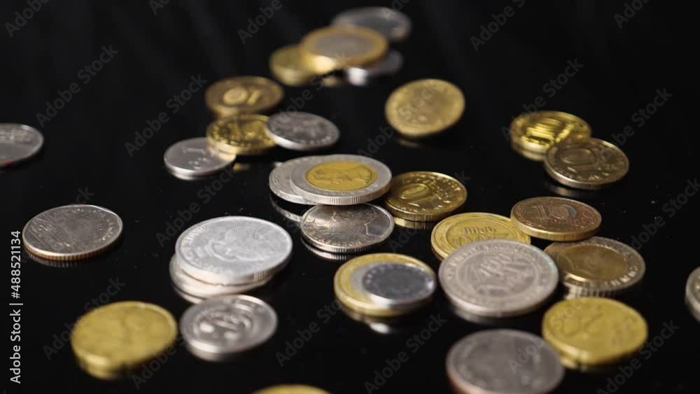 Close-up of coins from different countries of the world falling against a black background in slow motion. The concept of a global financial crisis Close-up of coins from different countries of the world falling against a black background in slow motion. The concept of a global financial crisis