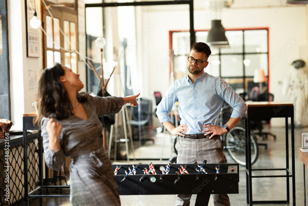 Colleagues having fun at work. Businessman and businesswoman playing table soccer.. Colleagues having fun at work. Businessman and businesswoman playing table soccer..