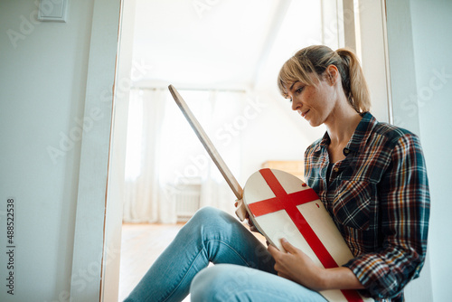 Woman sitting with wooden sword and shield at home photo