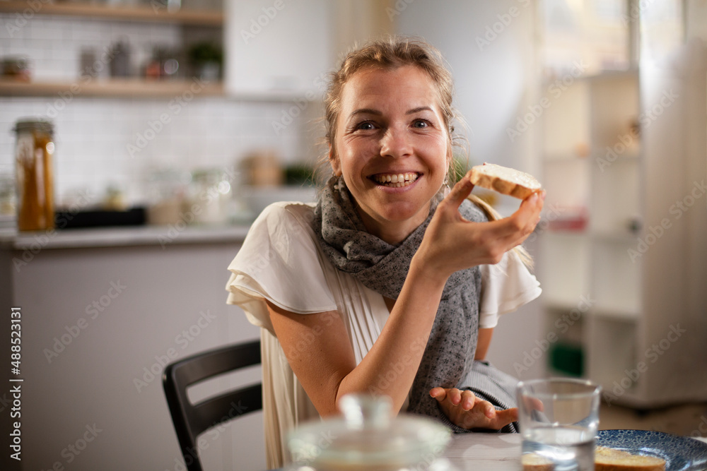 Beautiful woman enjoying in breakfast. Happy young woman eating sandwich at home Beautiful woman enjoying in breakfast. Happy young woman eating sandwich at home