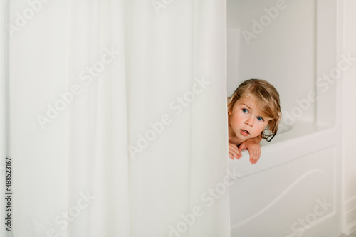 Cute girl peeking in bathtub photo