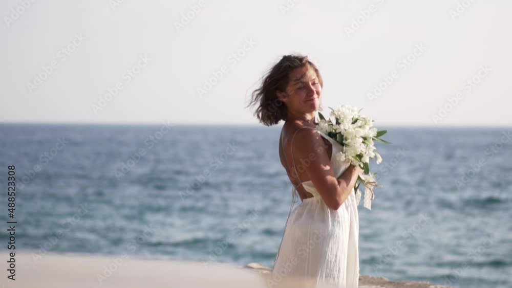 Beautiful girl with a bouquet of flowers on the background of the sea. High quality FullHD footage