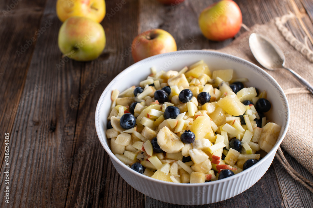 Bowl with fruit salad made with chopped apples, bananas, yellow kiwis and blueberries Bowl with fruit salad made with chopped apples, bananas, yellow kiwis and blueberries