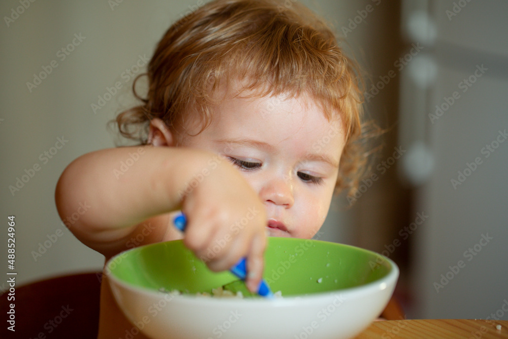 Family, food, child, eating and parenthood concept. Happy baby eating himself with a spoon. Family, food, child, eating and parenthood concept. Happy baby eating himself with a spoon.