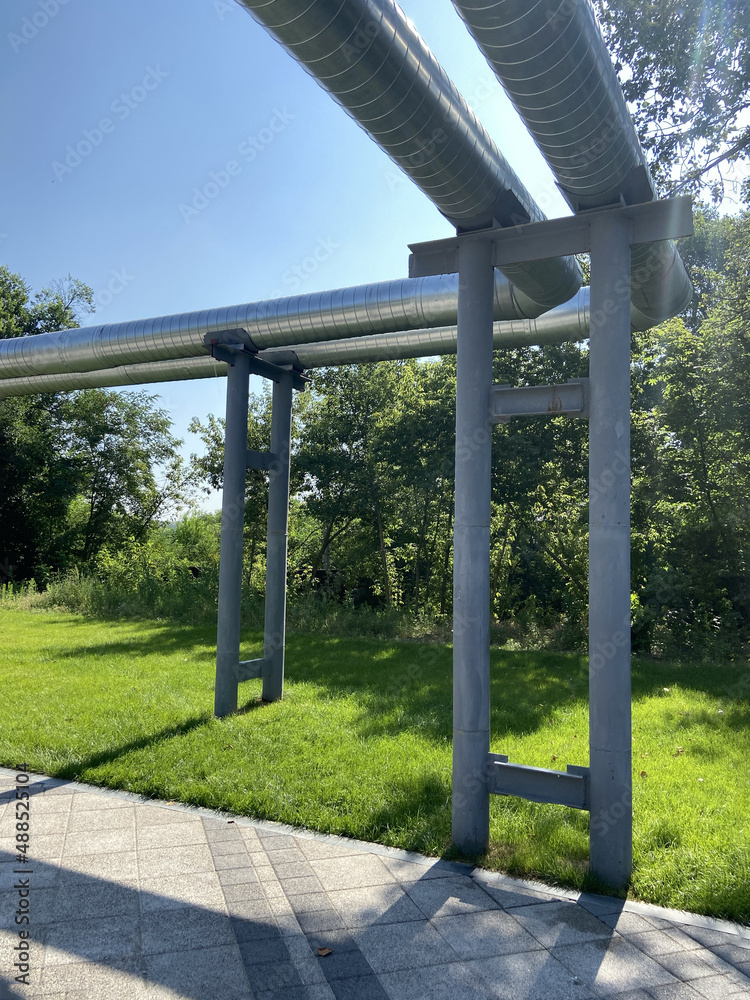 Oil and Gas Industry external pipelines among green trees and lawn, heating main Oil and Gas Industry external pipelines among green trees and lawn, heating main