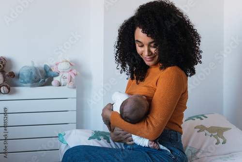 Mother breastfeeding baby boy in bedroom photo