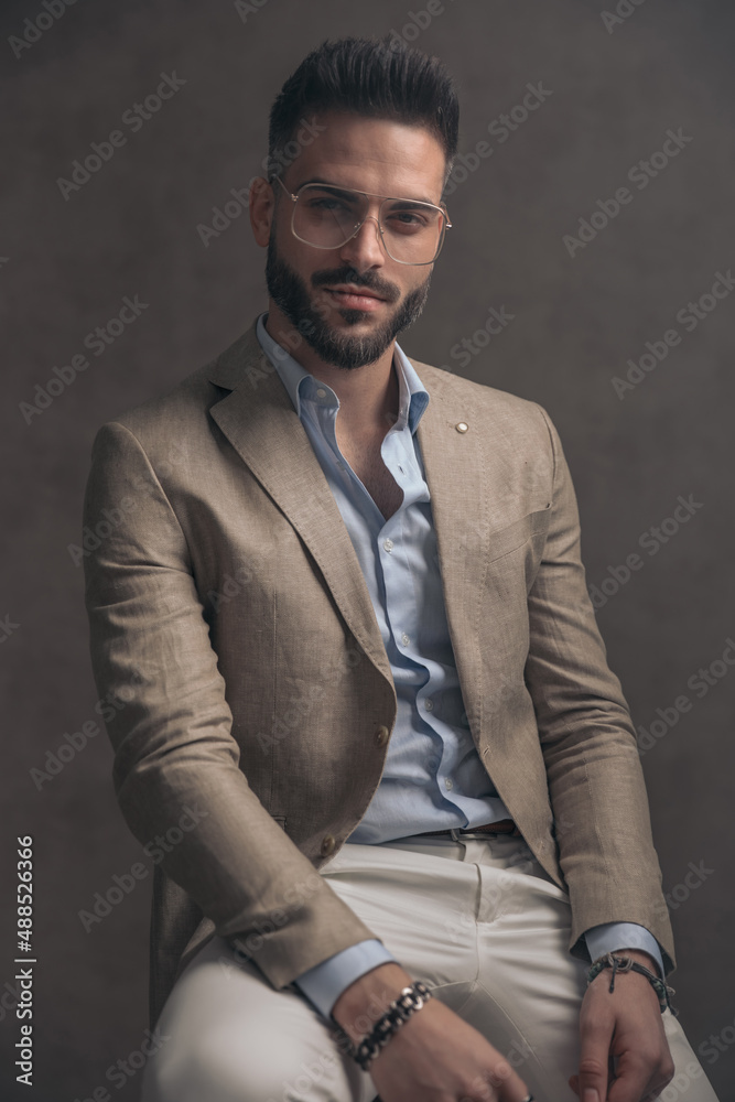 confident unshaved man with eyeglasses in beige suit sitting confident unshaved man with eyeglasses in beige suit sitting