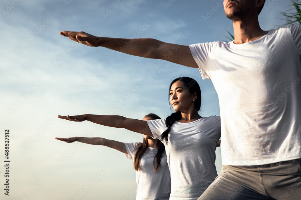 Group of people doing yoga exercises by the lake at sunset. Group of people doing yoga exercises by the lake at sunset.