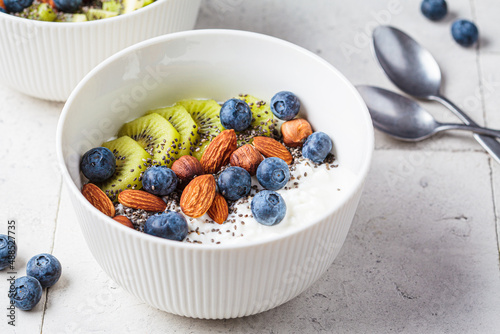 Breakfast cottage cheese with berries, nuts and chia seeds in white bowl. photo