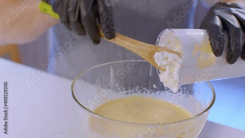 The pastry chef is pouring whipped cream into a bowl.