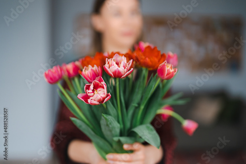 Happy woman enjoy bouquet of tulips. Housewife enjoying a bunch of flowers and interior of kitchen. Sweet home. Allergy free