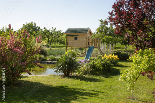 Children wooden playhouse in the beautiful garden near the lake