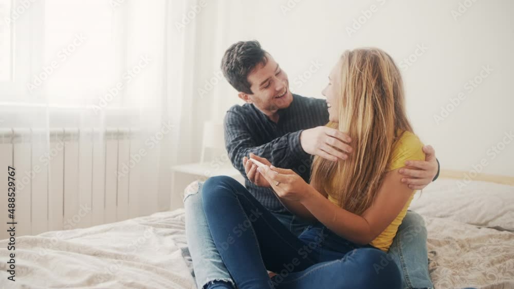 Future parents expecting a baby. Happy young girl surprises her boyfriend with a positive pregnancy test. Concept of love, family, relationship. Joy of maternity. Excited pair waiting future child. Future parents expecting a baby. Happy young girl surprises her boyfriend with a positive pregnancy test. Concept of love, family, relationship. Joy of maternity. Excited pair waiting future child.