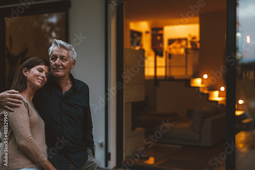 Senior man with woman standing in front of house at dusk