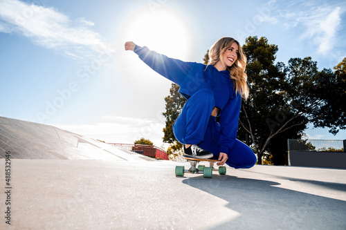 Cheerful caucasian woman skating with a skateboard in an urban environment