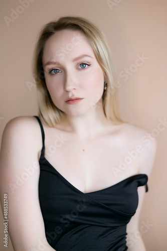 Graceful young woman posing against beige wall.