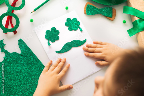 One toddler boy makes a postcard for the Patrick's Day holiday. Traditions, technologies, holidays concept.