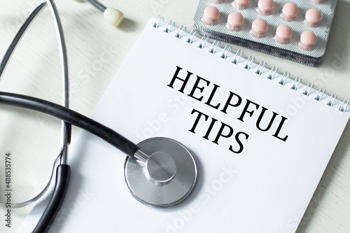 text HELPFUL TIPS on a notepad on the medical table. business and education concept