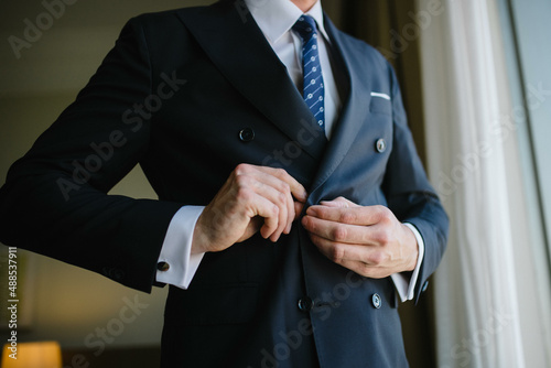 Young handsome man in classic suit. Young businessman puts on suit and prepares for a meeting.