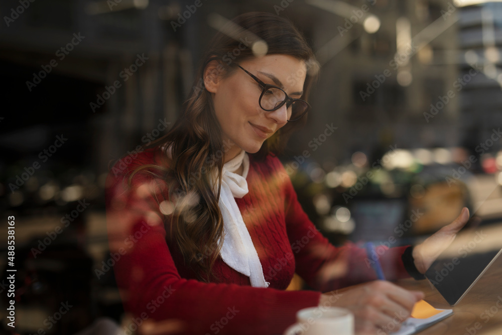 Beautiful young woman using digital tablet in cafe. Happy smiling woman enjoy in fresh coffee